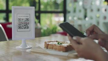 donna uso smartphone per scansione qr codice per pagare nel bar ristorante con un' digitale pagamento senza Contanti. scegliere menù e ordine accumulare sconto. e portafoglio, tecnologia, pagare in linea, credito carta, banca App video