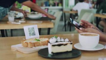 une femme utilise un smartphone pour scanner le code qr pour payer au café-restaurant avec un paiement numérique sans espèces. choisissez le menu et commandez accumulez la réduction. portefeuille électronique, technologie, paiement en ligne, carte de crédit, application bancaire video