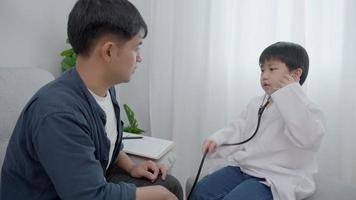 Asia children plays the doctor recheck healthy for father on weekend. boy has a dream in a doctor's career. The concept of family activities and the dream. Holiday, imagine future. video