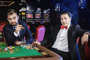 Handsome guys drinking cognac and playing roulette in the casino photo