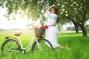 mujer en bicicleta está recogiendo manzanas frescas del árbol en el jardín del pueblo foto