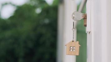 Landlord house key for unlocking a house is plugged into the door. Second hand house for rent and sale. keychain is blowing in the wind. Landlord for new house, rent , sale, renovate, investment. video