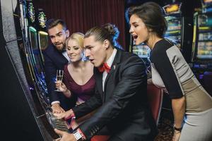 Group of friends playing slot machines in casino photo