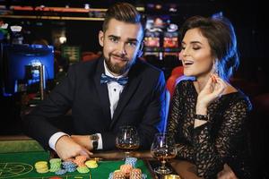 hermosa y rica pareja jugando a la ruleta en el casino foto