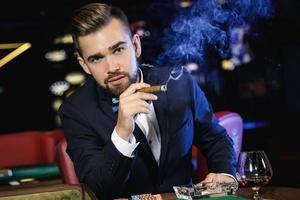 Rich handsome man smoking cigar in the casino photo