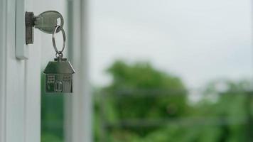 Landlord house key for unlocking a house is plugged into the door. Second hand house for rent and sale. keychain is blowing in the wind. Landlord for new house, rent , sale, renovate, investment. video