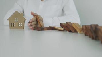 l'assurance avec les mains protège le domino. les mains de l'homme d'affaires empêchent les dominos de tomber dans la crise des affaires. contrôle des risques commerciaux et planification et stratégies pour gérer les entreprises d'assurance. video