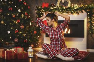 Happy woman sitting beside the fireplace in Christmas decorations photo