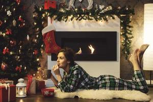 Woman lying beside fireplace is drinking hot tea with cookies photo