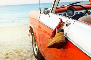 Car with tied boots and bandana to a door handle on the beach photo