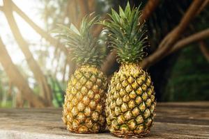Two ripe pineapple fruits on wooden surface photo