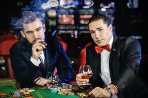 Handsome guys drinking cognac and playing roulette in the casino photo