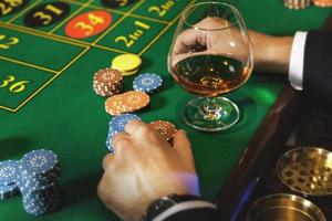 Man playing roulette in casino. Close up of male hands with a glass of cognac and chips. photo