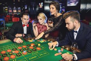 gente joven y rica jugando a la ruleta en el casino foto