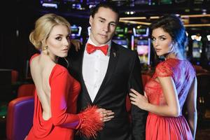 Confident man and two beautiful women in the casino photo