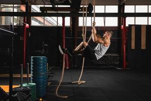 Sportsman doing rope climbing exercise in cross training gym photo