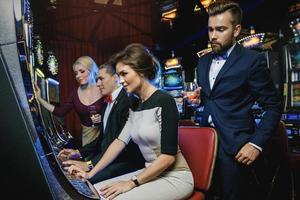 Group of friends playing slot machines in casino photo