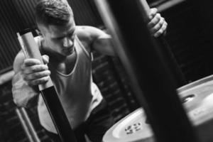 deportista fuerte durante el ejercicio de empuje de trineo en el gimnasio de entrenamiento cruzado foto