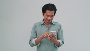 les hommes asiatiques sont accros à leurs téléphones et souriront avec plaisir en utilisant des téléphones. l'homme utilise son téléphone pour jouer à Internet pour se détendre du travail. un homme heureux sourit après avoir utilisé le téléphone pour remettre son travail. video