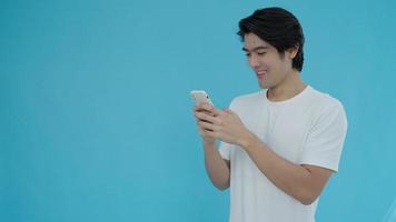 Asien-Mann überprüft Chat und lächelt auf dem Handy. gutaussehende männer, die während der nutzung von technologie, internet und kommunikation sehr glücklich sind. technologie für ein glückliches konzept.