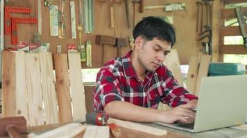 Asian business owners are checking drawing use tape inspection wood for confirm design to customer. Carpenter use computer design furniture for renovate town home. video