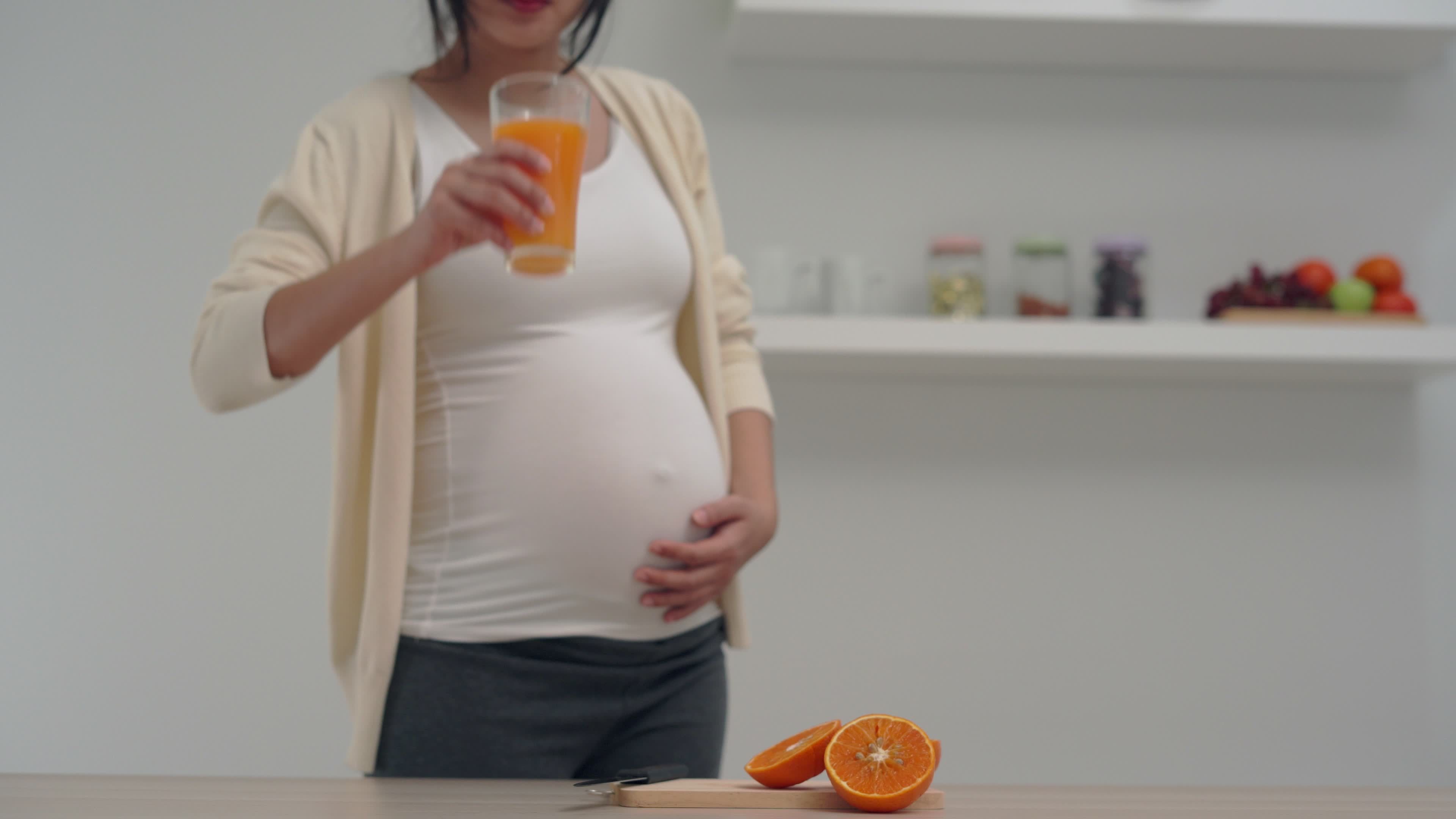 A pregnant woman is juicing orange juice to add vitamins to her unborn child. Pregnant women