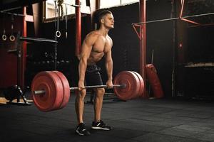 Deadlift exercise. Man during his workout in the gym photo