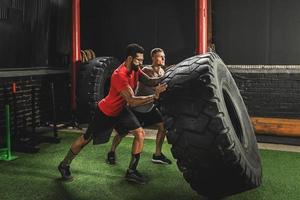 Two strong men doing a tire flip exercise photo