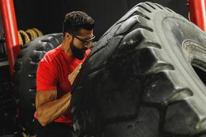 Strong sportsman doing a tire flip exercise photo