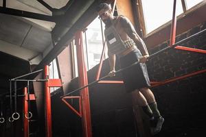 Strong man doing muscle up exercise in cross training gym photo