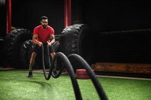 Man is making battle rope exercises in the cross training gym photo