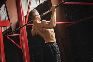 Strong man doing pull up exercise in the gym photo