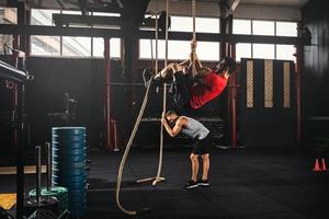 Two men doing rope climbing exercise in the cross training gym photo