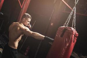 Strong young mma fighter and red punching bag photo