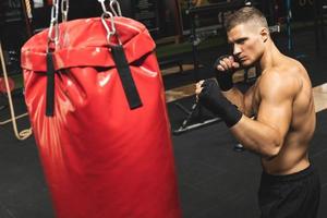 luchador de mma joven y fuerte y saco de boxeo rojo foto