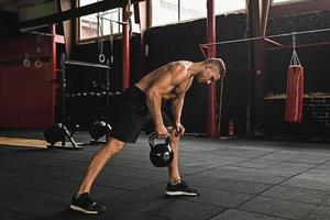 Sportsman doing exercises with a kettlebell in the gym photo