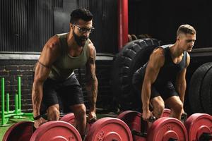 Muscular men during competition in the farmer's walk exercise photo