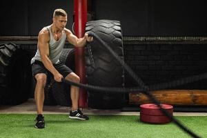 Man is making battle rope exercises in the cross training gym photo