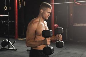 Young handsome bodybuilder during his arm workout in the gym photo