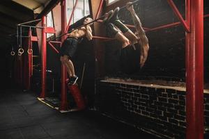 Two strong men doing exercise on bars in the gym photo