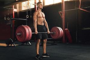 Deadlift exercise. Man during his workout in the gym photo