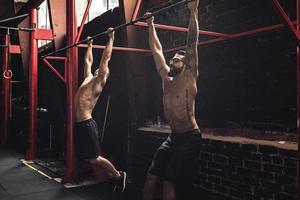 Two strong men doing exercise on bars in the gym photo