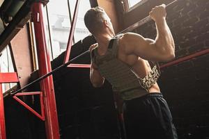 Strong man doing pull up exercise in cross training gym photo