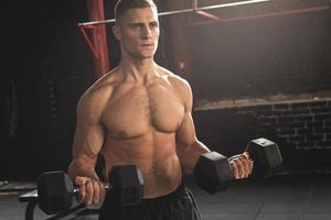 Young handsome bodybuilder during his arm workout in the gym photo