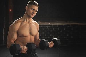 Young handsome bodybuilder during his arm workout in the gym photo