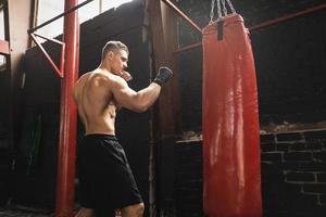 Strong young mma fighter and red punching bag photo