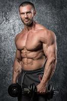 Bodybuilder man doing exercises with heavy dumbbells photo