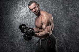 Bodybuilder man doing exercises with heavy dumbbells photo