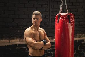 luchador de mma joven y fuerte y saco de boxeo rojo foto