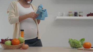Happy pregnant woman in a good mood is happily clean the kitchen and clean a glass. Pregnant women do housework to relax and recreation. Activity at home for pregnant women. video